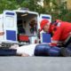 Ambulance crew helping unconscious man on road, first aid at car accident scene