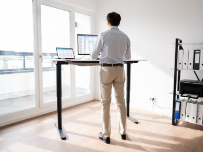 Man Working On Computer At Standing Desk In Home Office
