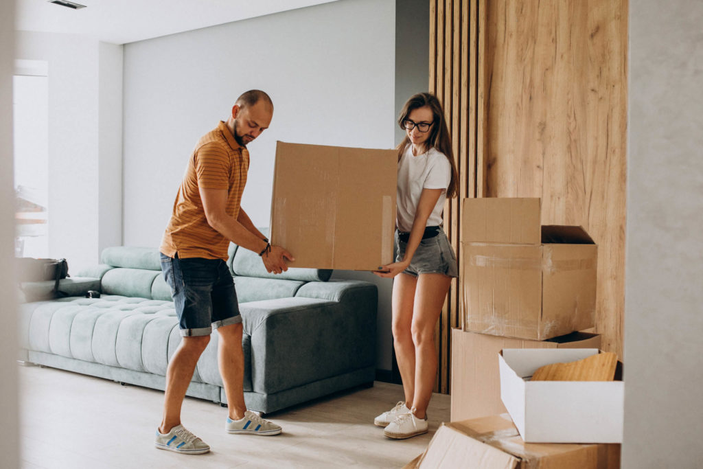 Young couple moving boxes inside their new home