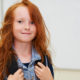 Red head girl going back to school with backpack in the classroom