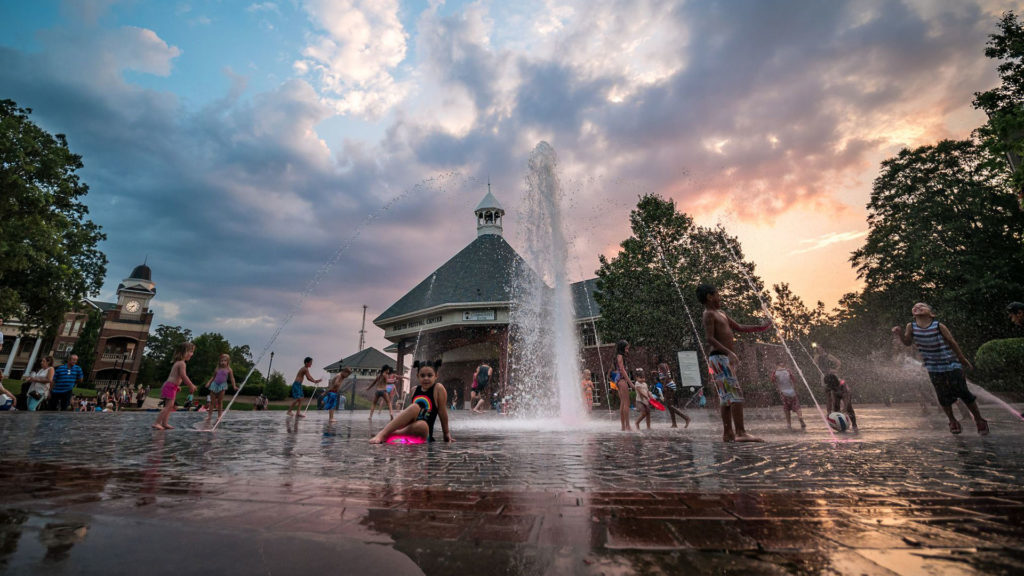 Image of kids playing in water jets in downtown Duluth GA. If you are moving to Duluth GA, make sure you enjoy the summer months down by City Hall.