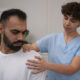 A chiropractor examining a patient's shoulder and neck area for thoracic outlet syndrome treatment.
