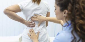 Doctor examining a patient's back to evaluate spinal decompression techniques for relieving discomfort from scoliosis pain.