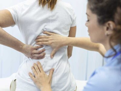 Doctor examining a patient's back to evaluate spinal decompression techniques for relieving discomfort from scoliosis pain.