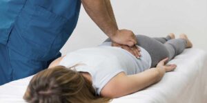 Therapist applying manual spinal decompression on a patient's lower back to relieve pain caused by a pinched nerve.