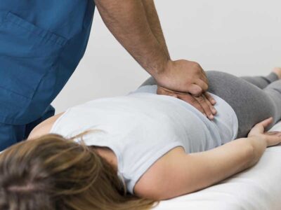 Therapist applying manual spinal decompression on a patient's lower back to relieve pain caused by a pinched nerve.