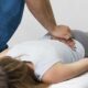 Therapist applying manual spinal decompression on a patient's lower back to relieve pain caused by a pinched nerve.