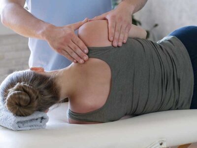 Patient wearing comfortable athletic tank top and leggings lying on treatment table during spinal adjustment at a chiropractor appointment.